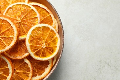 Photo of Bowl of dry orange slices on light table, top view. Space for text