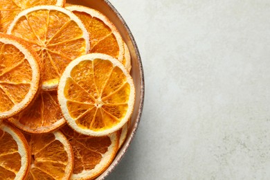 Bowl of dry orange slices on light table, top view. Space for text