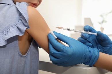 Doctor giving injection to little girl in hospital, closeup. Immunization concept