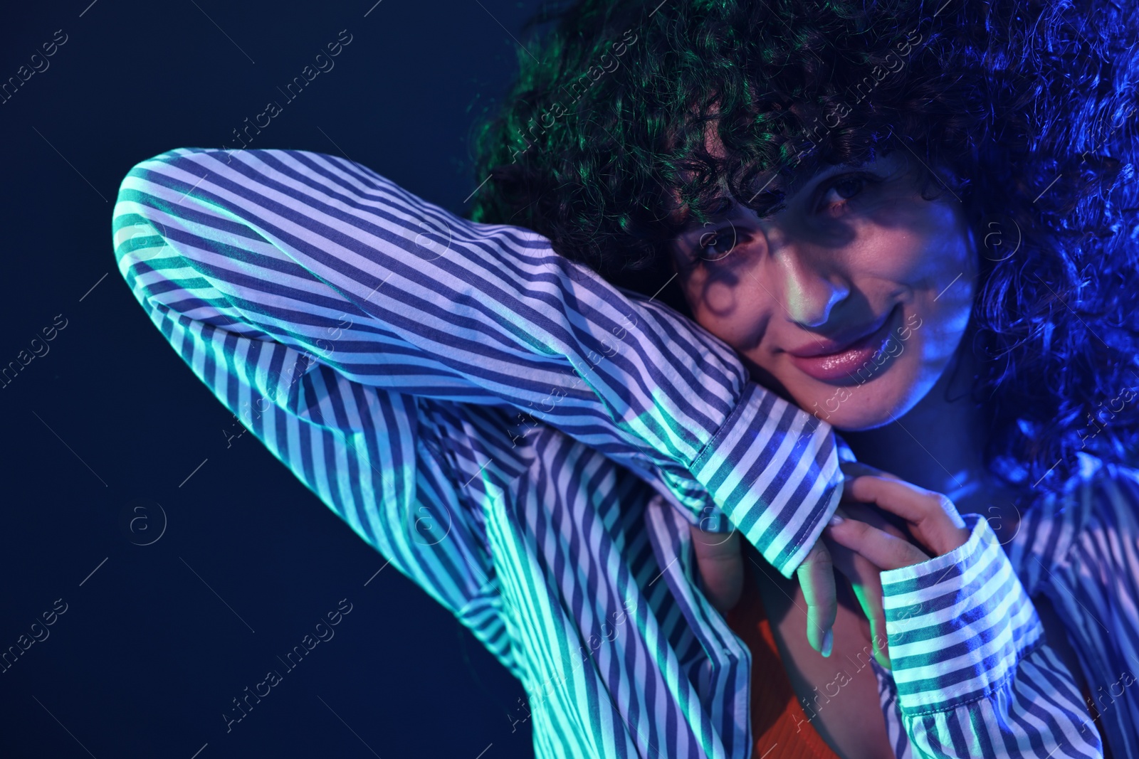 Photo of Beautiful young woman posing on color background in neon lights, closeup