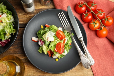 Delicious salad with crab sticks and tomatoes on wooden table, flat lay