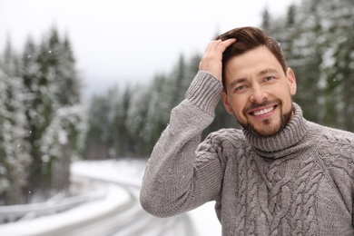 Photo of Man in warm sweater outdoors on snowy day, space for text. Winter vacation