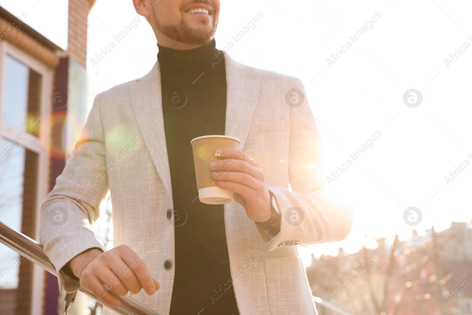 Photo of Businessman with cup of coffee on city street in morning, closeup