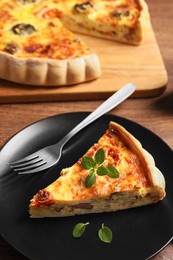 Delicious homemade vegetable quiche, oregano and fork on wooden table