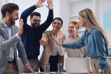 Photo of Team of employees celebrating success in office