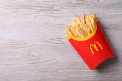 Photo of MYKOLAIV, UKRAINE - AUGUST 12, 2021: Big portion of McDonald's French fries on white wooden table, top view. Space for text