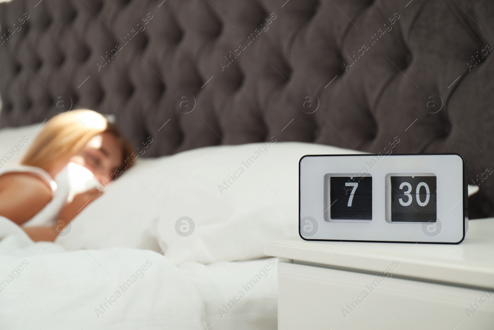 Photo of Digital alarm clock and blurred sleepy woman on background. Time of day