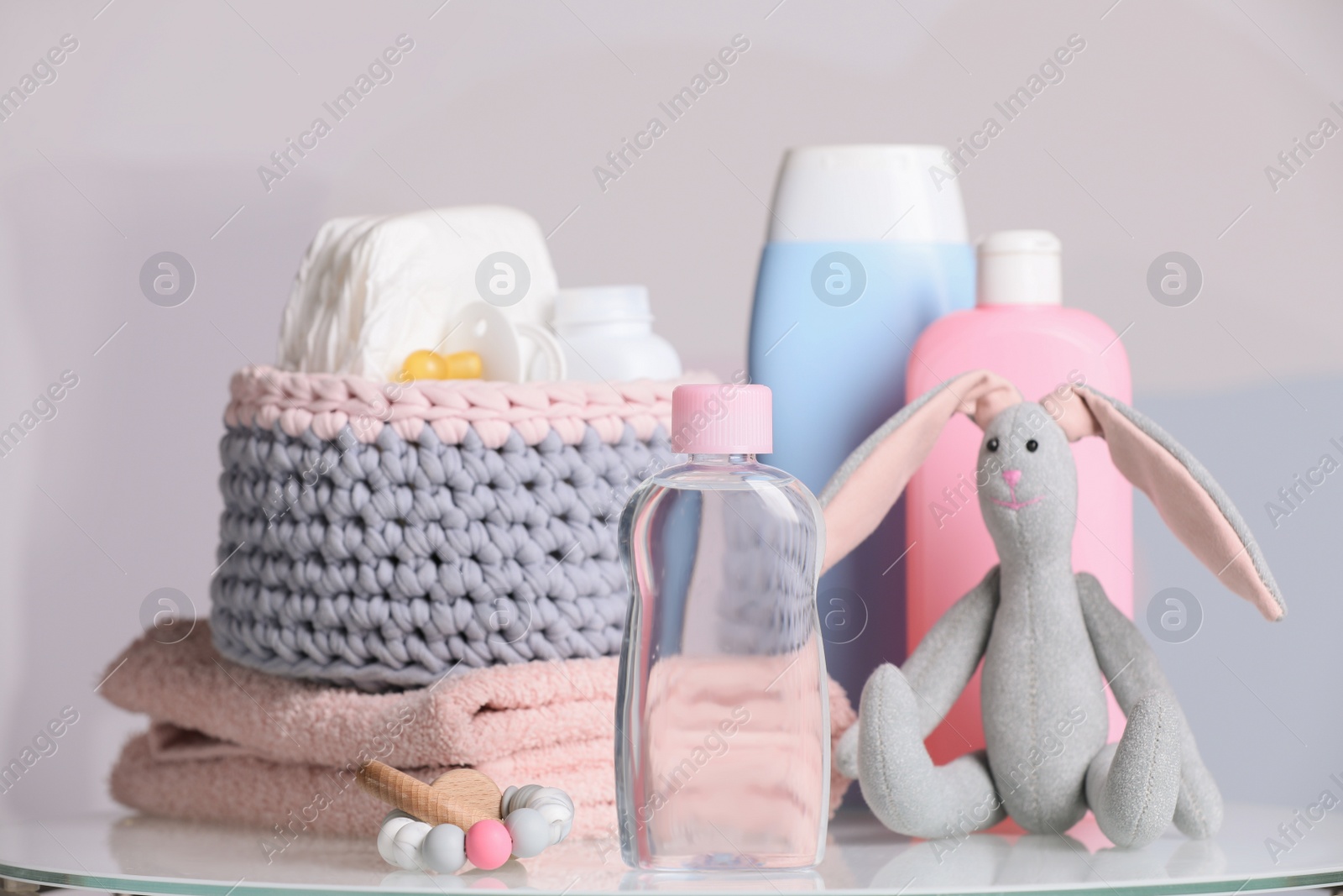 Photo of Baby cosmetic products, toys and accessories on white table against color background