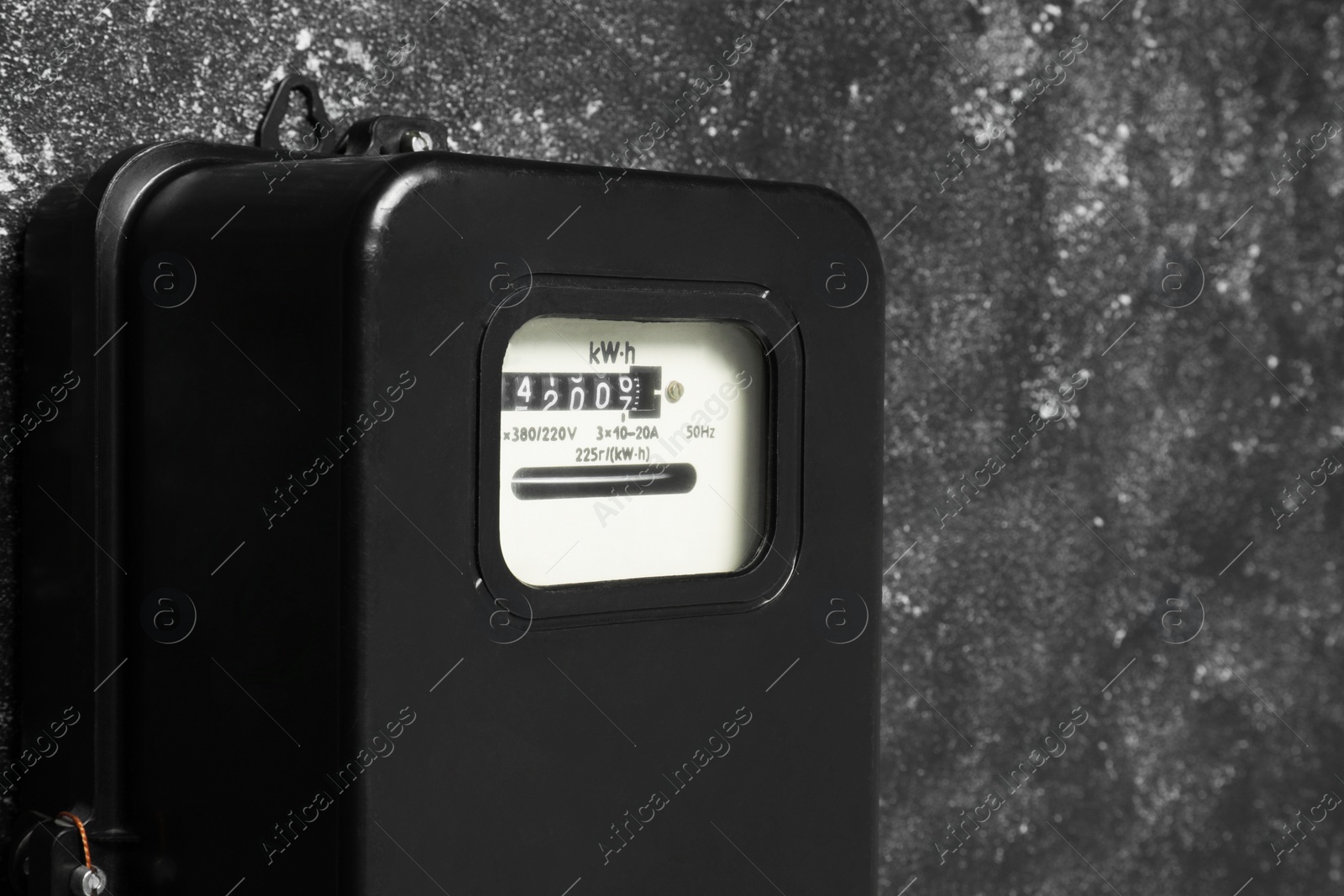 Photo of Electricity meter on grey wall, closeup and space for text