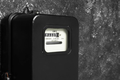 Electricity meter on grey wall, closeup and space for text