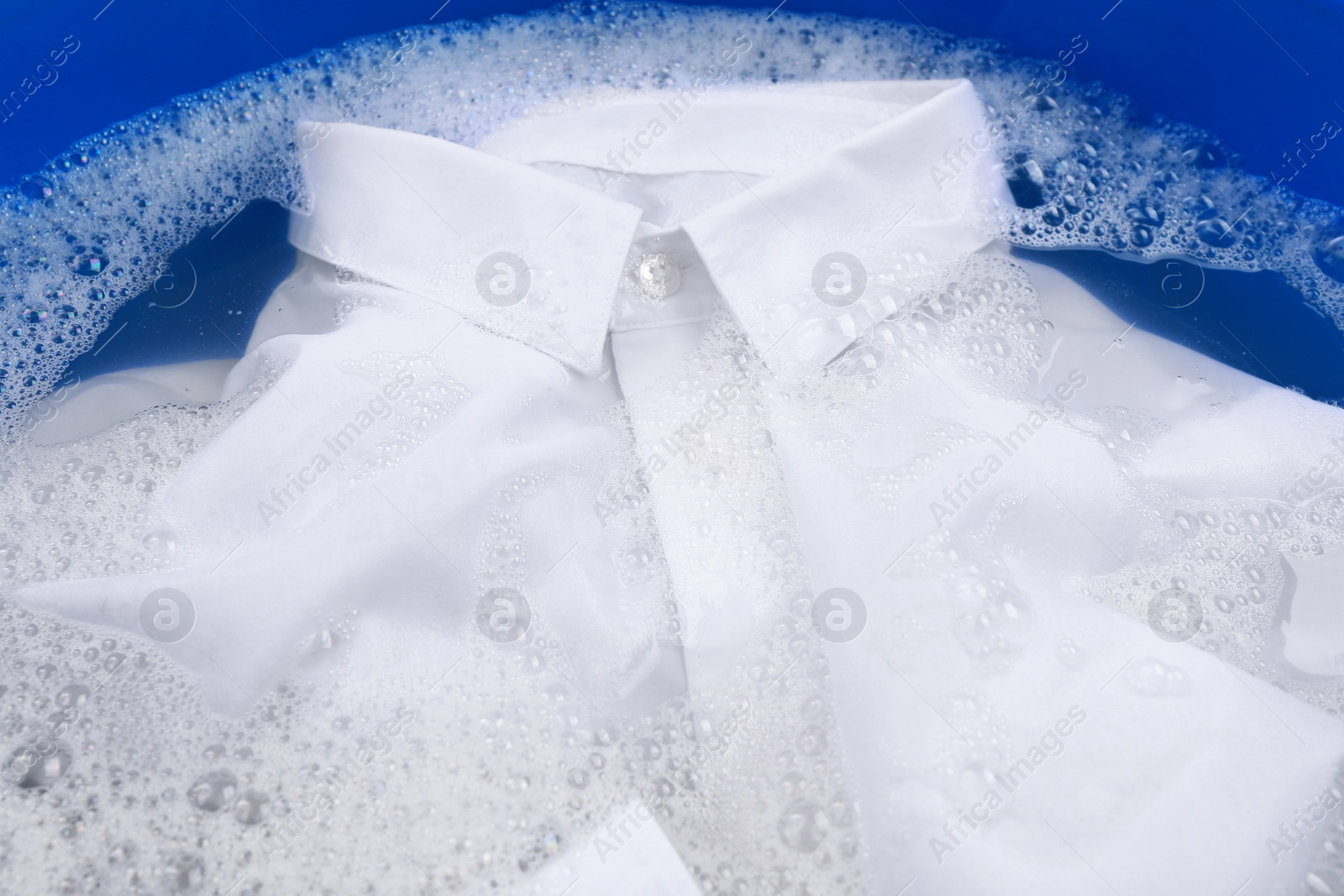 Photo of White shirt in suds, closeup. Hand washing laundry