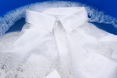 Photo of White shirt in suds, closeup. Hand washing laundry