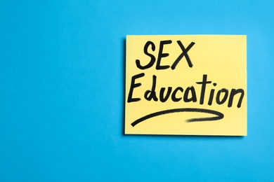 Photo of Note with phrase "SEX EDUCATION" on blue background, top view. Space for text