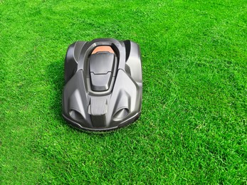 Photo of Modern robot lawn mower on green grass in garden