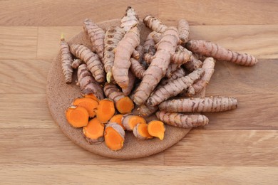Board with fresh turmeric roots on wooden table, above view