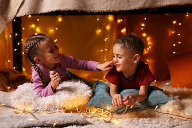 Happy kids playing in decorated play tent at home