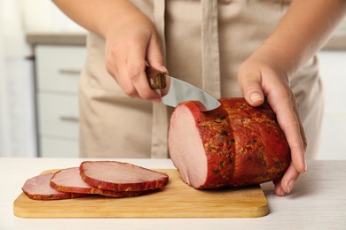 Photo of Woman cutting ham at table in kitchen, closeup