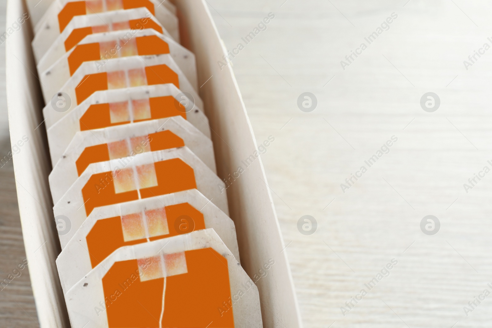 Photo of Box with paper tea bags on wooden table, closeup. Space for text