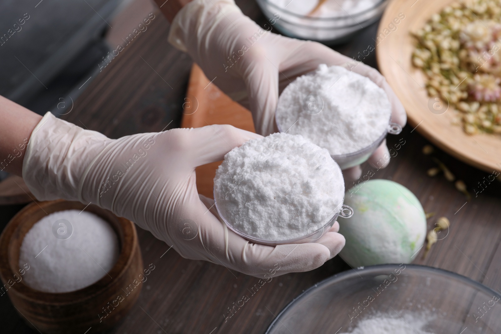 Photo of Woman in gloves making bath bomb at table, closeup