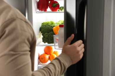 Photo of Young man opening refrigerator at home, closeup