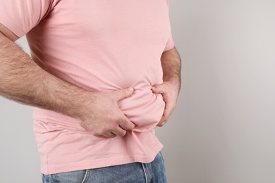 Overweight man with large belly on color background, closeup. Space for text