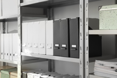 Photo of Folders and boxes with documents on shelves in archive