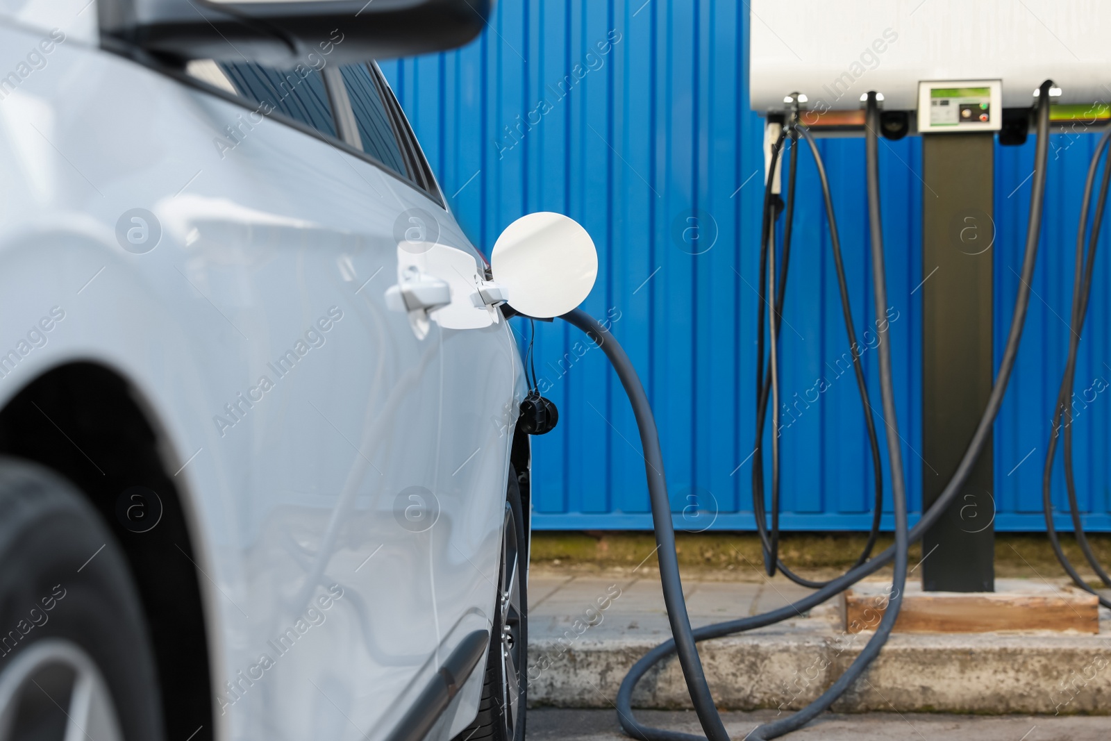 Photo of Charging modern electric car from station outdoors