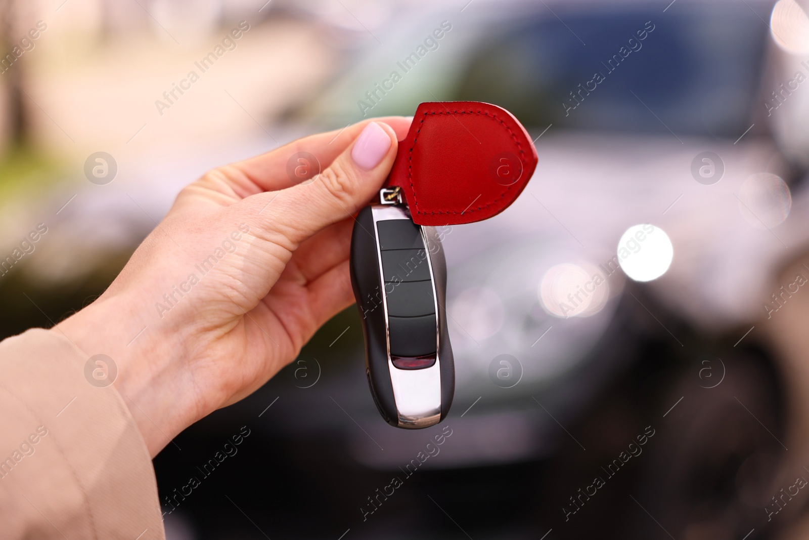 Photo of Woman holding car flip key near her vehicle outdoors, closeup