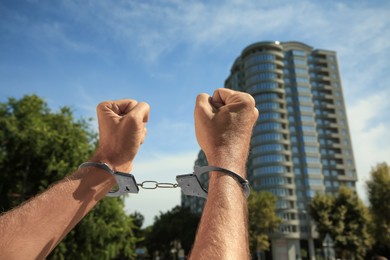 Man in handcuffs outdoors on sunny day, closeup
