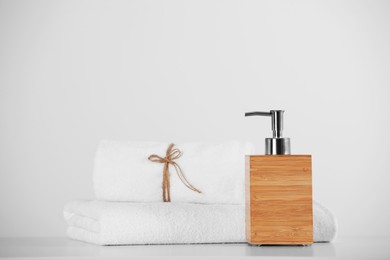 Photo of Soft towels and wooden dispenser on white table
