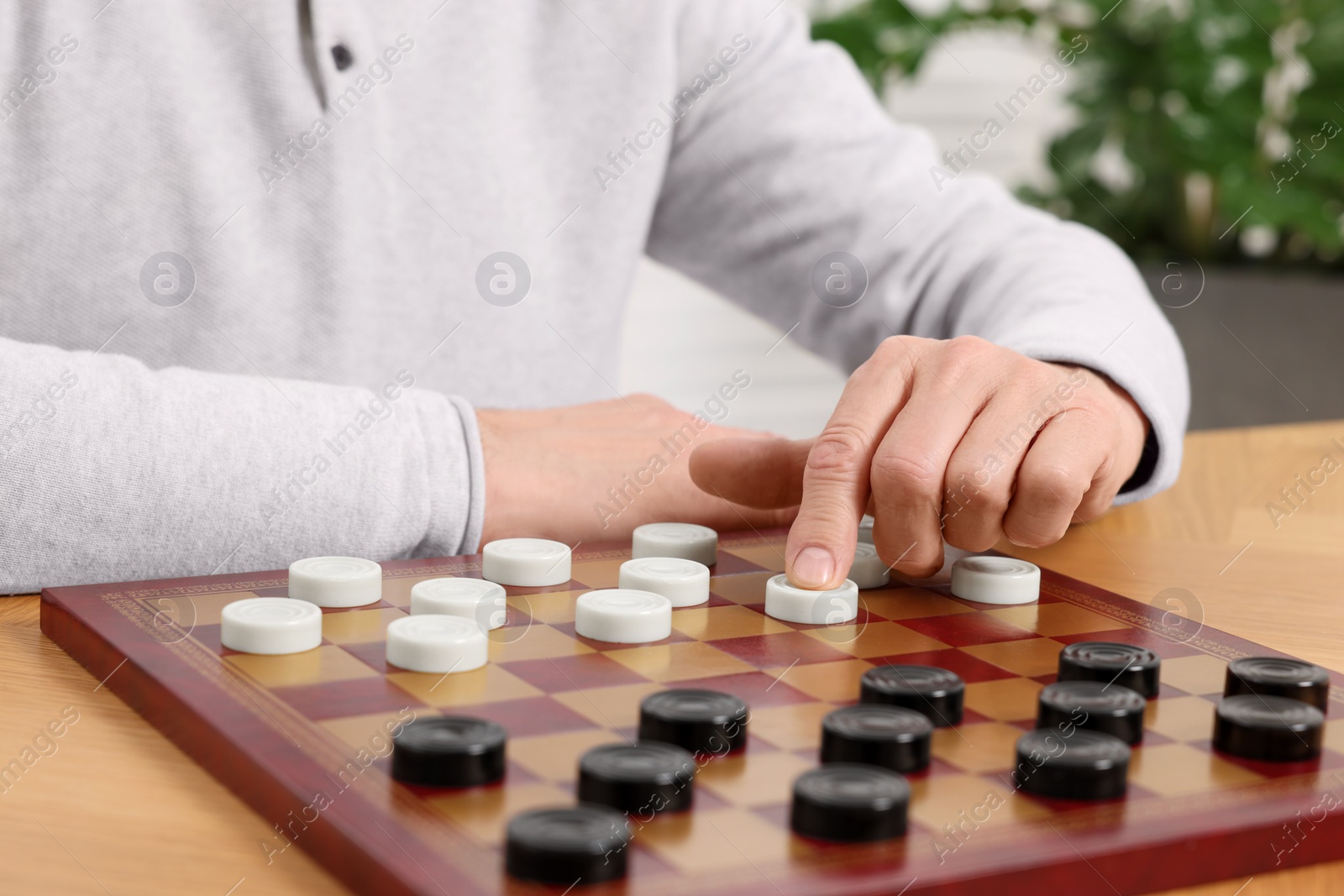 Photo of Playing checkers. Senior man thinking about next move at table in room, closeup