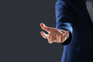 Photo of Businessman holding something in hand on dark background