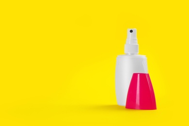 Bottle with insect repellent spray on yellow background, space for text