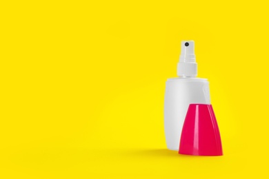 Photo of Bottle with insect repellent spray on yellow background, space for text