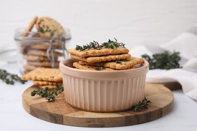 Photo of Cereal crackers with flax, sesame seeds and thyme in bowl on light table, closeup