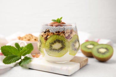 Delicious dessert with kiwi, chia seeds and almonds on light table, closeup