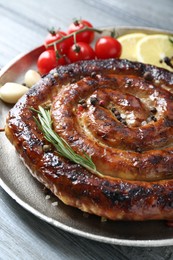 Delicious homemade sausage with spices, tomatoes and lemon on light grey wooden table, closeup