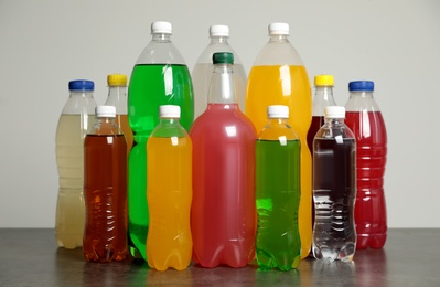 Photo of Bottles of soft drinks on table against grey background