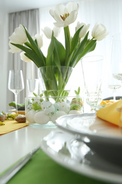 Photo of Festive table setting with Easter decorative eggs in bowl and white tulips