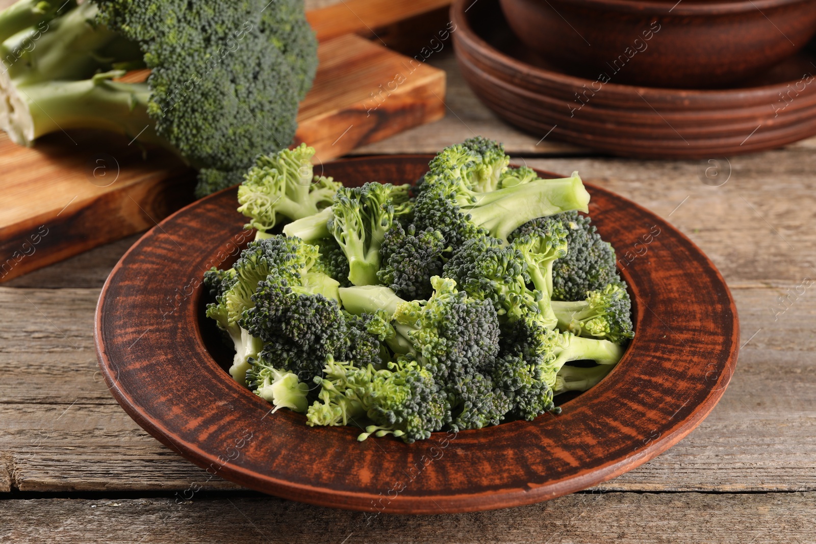 Photo of Plate with fresh raw broccoli on wooden table, closeup