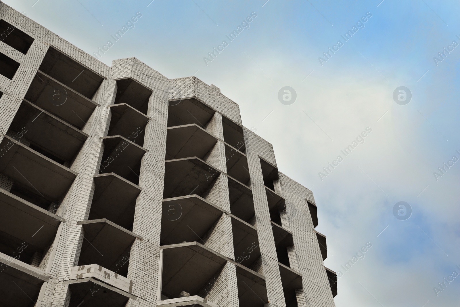 Photo of Construction site with unfinished building under cloudy sky, low angle view