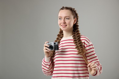 Woman with braided hair taking photo on grey background, space for text