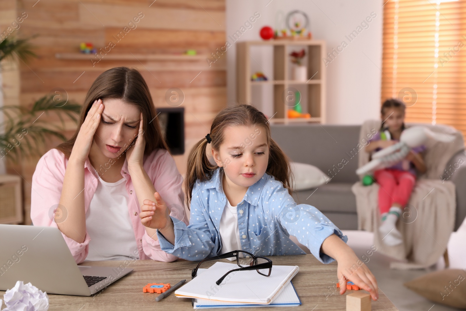 Photo of Children disturbing stressed woman in living room. Working from home during quarantine