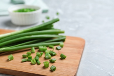 Photo of Wooden board with bunch of fresh green onion on table, closeup