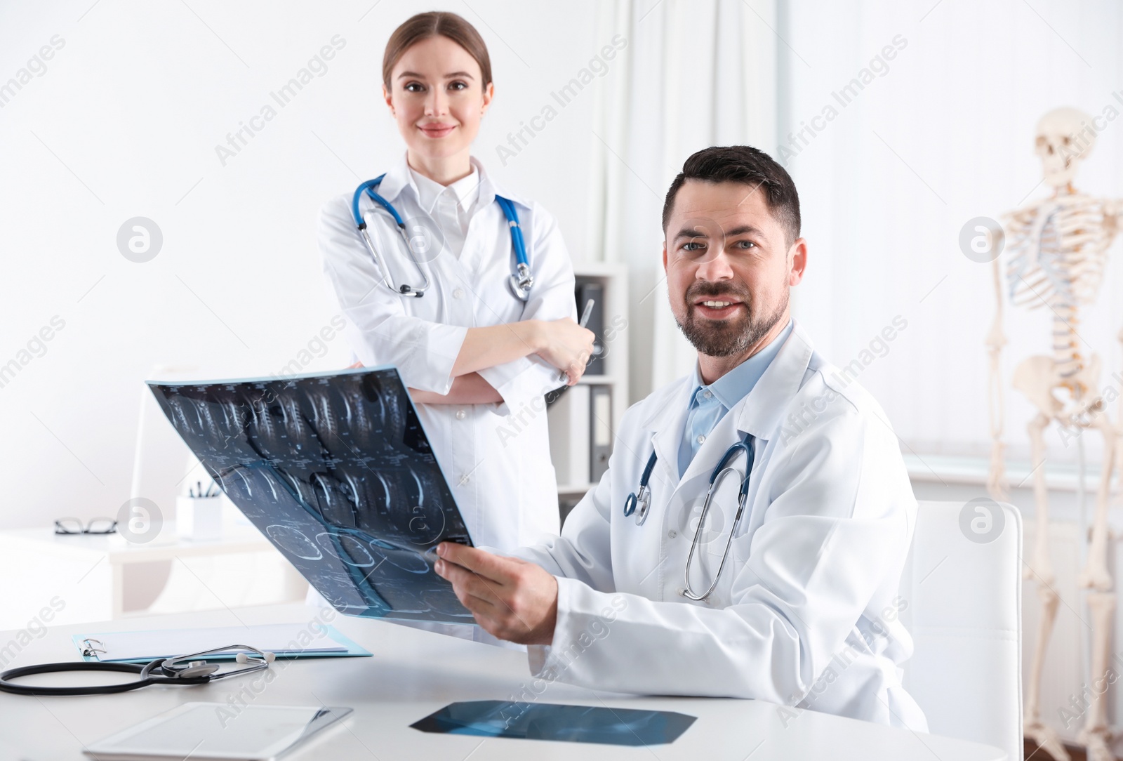 Photo of Orthopedists examining X-ray picture at desk in clinic