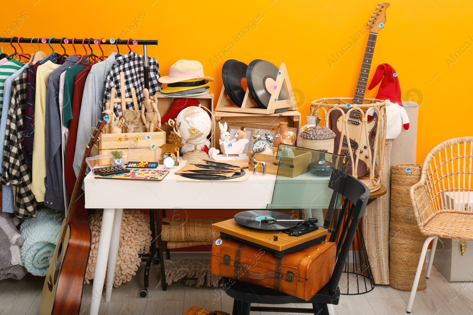 Photo of Many different stuff near orange wall indoors. Garage sale