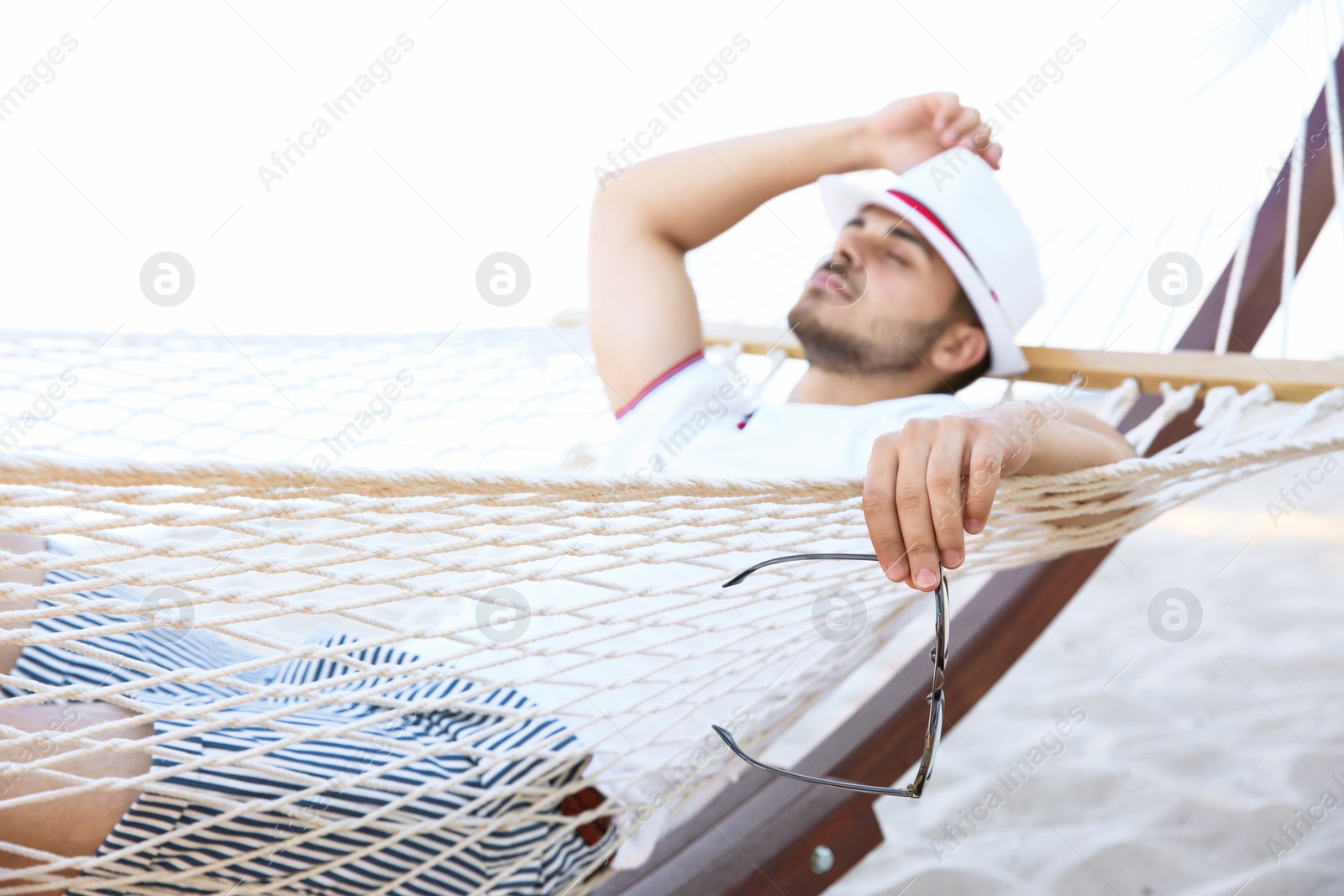 Photo of Young man resting in hammock at seaside. Summer vacation