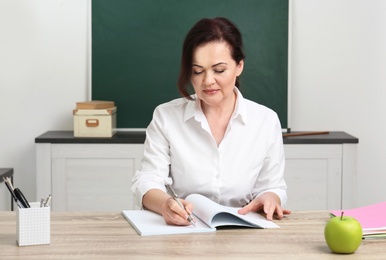Portrait of female teacher sitting at table in classroom