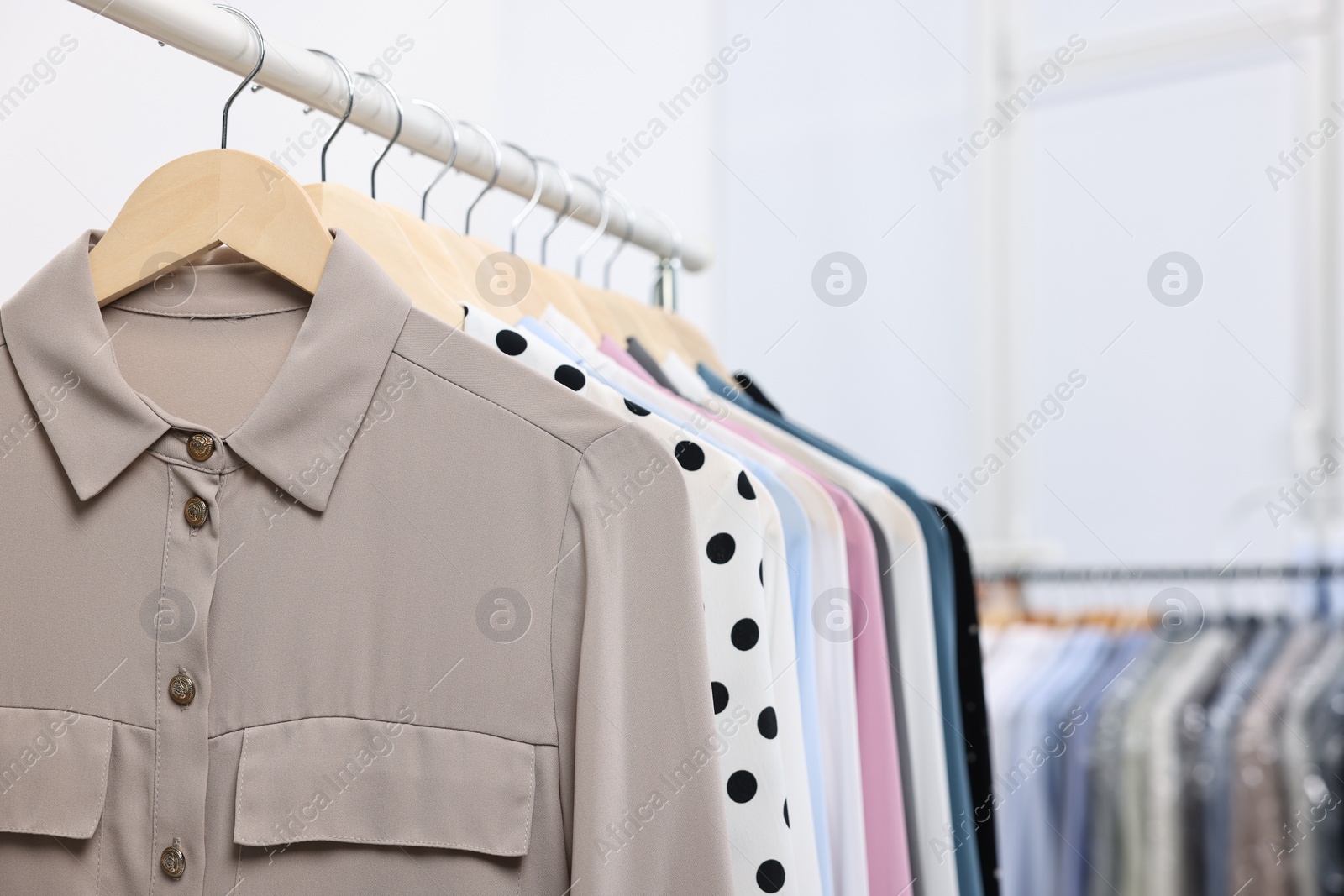 Photo of Dry-cleaning service. Many different clothes hanging on rack indoors, closeup