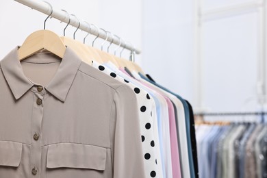 Dry-cleaning service. Many different clothes hanging on rack indoors, closeup